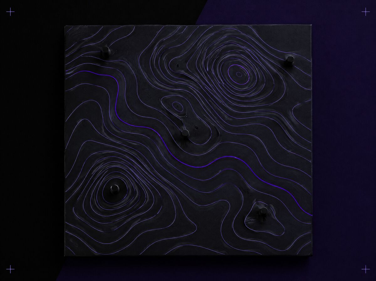 A black plate carved with lavender topographic contour lines and a few small pins; one contour line is highlighted in violet.